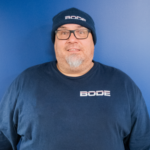 Clay Patles headshot with blue wall and BODE clothing