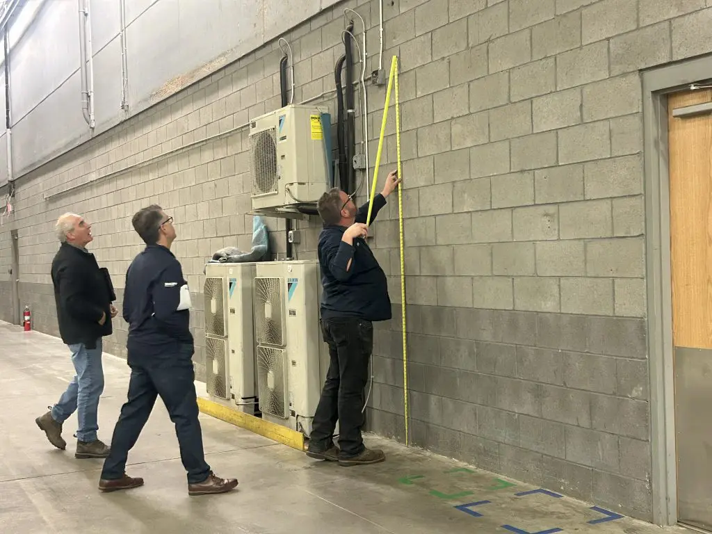 Rich using measuring tape empty warehouse